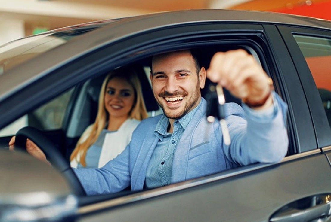 Happy couple at car window thumbs up