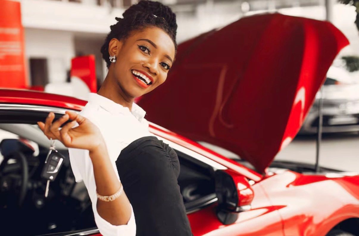 Woman beside red car at dealership